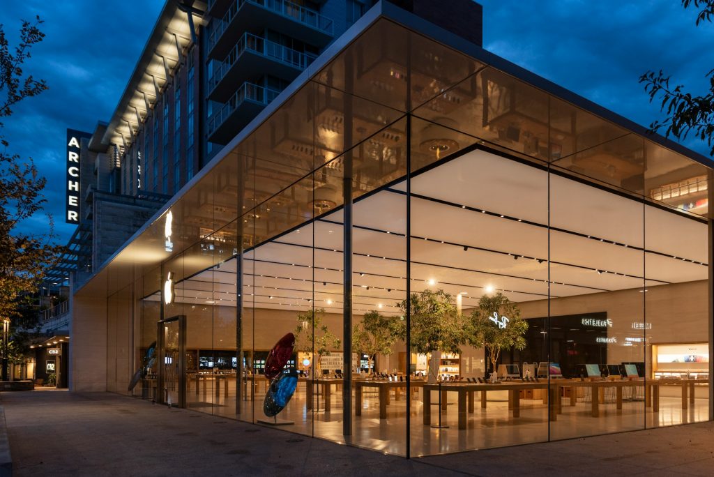 a large glass building with a tree in front of it